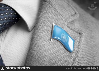Metal badge with the flag of International Intellectual Property Organization on a suit lapel.. Metal badge with the flag of International Intellectual Property Organization on a suit lapel
