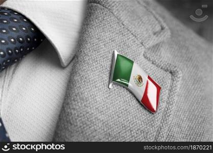 Metal badge with the flag of Mexico on a suit lapel.. Metal badge with the flag of Mexico on a suit lapel