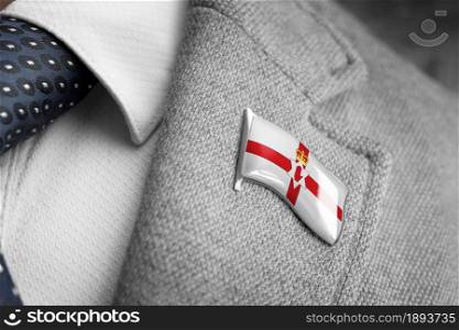 Metal badge with the flag of Northern Ireland on a suit lapel.. Metal badge with the flag of Northern Ireland on a suit lapel