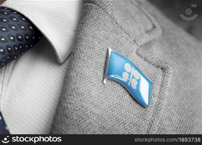 Metal badge with the flag of Organization of the Petroleum Exporting Countries on a suit lapel.. Metal badge with the flag of Organization of the Petroleum Exporting Countries on a suit lapel