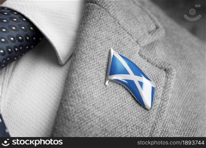 Metal badge with the flag of Scotland on a suit lapel.. Metal badge with the flag of Scotland on a suit lapel