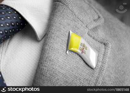 Metal badge with the flag of Vatican on a suit lapel.. Metal badge with the flag of Vatican on a suit lapel