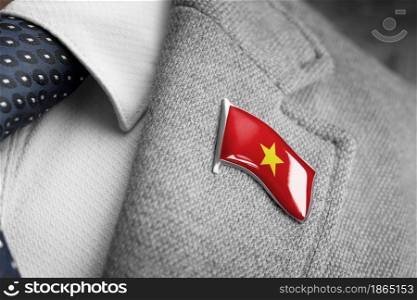 Metal badge with the flag of Vietnam on a suit lapel.. Metal badge with the flag of Vietnam on a suit lapel