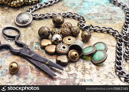 Metal beads,buttons,chain and scissors on retro background