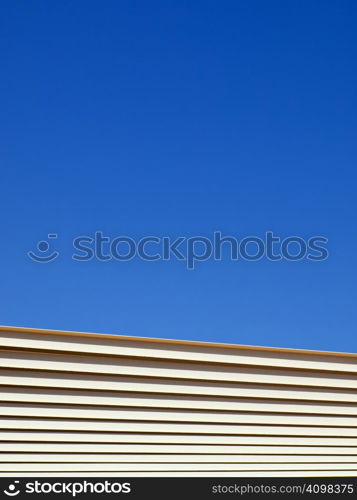 Metal beams from an outdoor structure stretch across a clear blue sky.