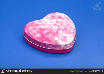 Metal box in shape of heart on blue background
