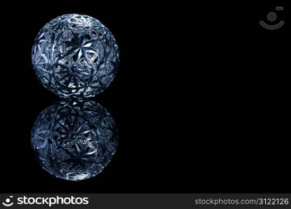 metal christmas ball on a black mirror. blue metal christmas ball on a black mirror on black background