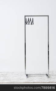 Metal clothing rail with empty coat hangers. Rectangular metal clothing rail with empty coat hangers standing on a white carpet against an off white wall with copyspace