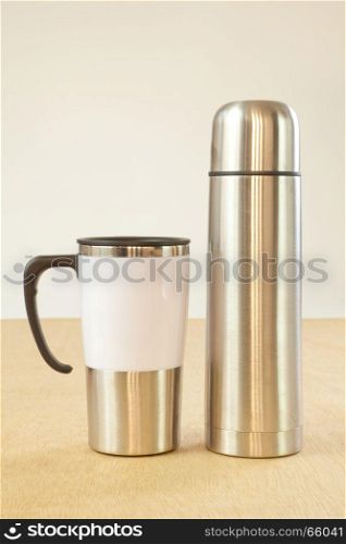 metal cup and water bottle on wood background