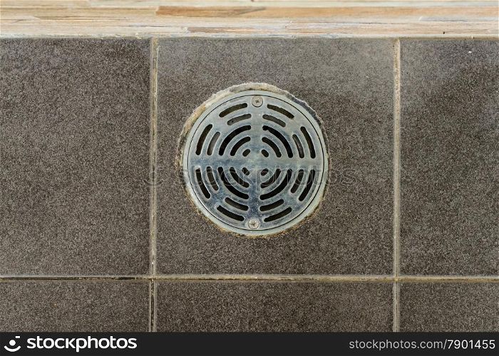 Metal drain hole in the tiled floor of a shower