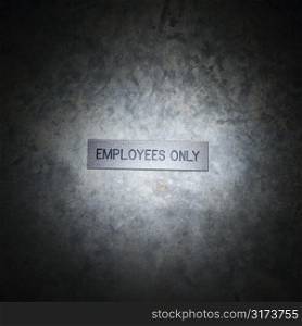 Metal employees only sign on textured background.