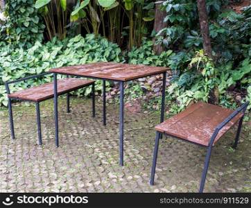 Metal frame table and chair set on the brick floor for resting in the botanical garden.