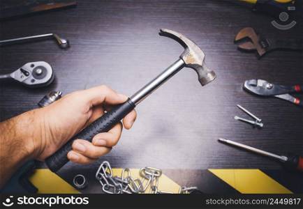 Metal hammer tool on the hand of mechanic with mechanic tools on backdrop
