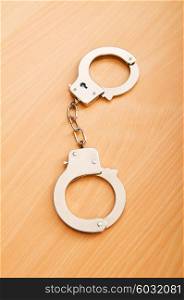 Metal handcuffs on the wooden background