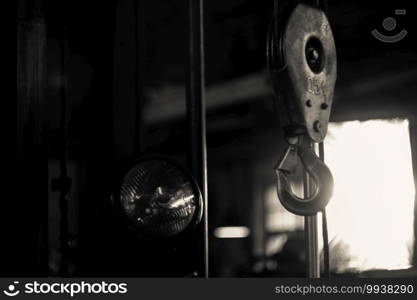 Metal hook from a crane against the background of a workshop. A piece of metal or other material, curved or bent back at an angle, for catching hold of or hanging things on.