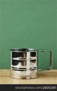 metal jug on old wooden table over green background