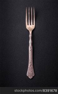 Metal kitchen fork on a dark textured concrete background. Cutlery, preparation for dinner