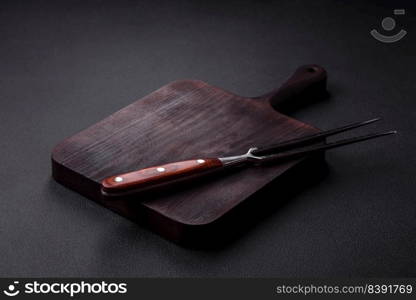 Metal kitchen fork on a dark textured concrete background. Cutlery, preparation for dinner