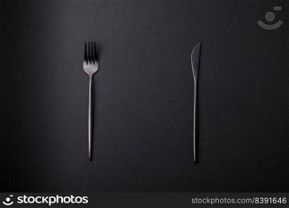 Metal kitchen knife and fork on a dark textured concrete background. Cutlery, preparation for dinner