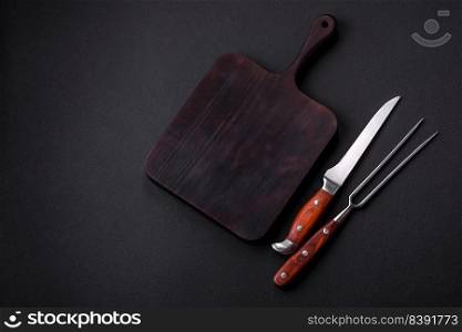 Metal kitchen knife and fork on a dark textured concrete background. Cutlery, preparation for dinner