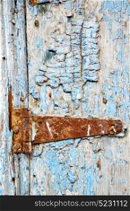 metal nail dirty stripped paint in the brown red wood door and rusty knocker