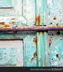 metal nail dirty stripped paint in the brown red wood door and rusty knocker