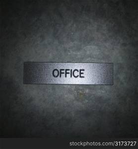 Metal office sign on textured background.