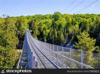 Metal pedestrian suspension bridge over Ranney Gorge in Campbellford, Ontario, Canada.