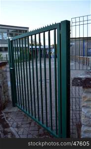 Metal railing of green color which closes enters him of a school
