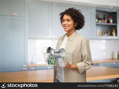 metal recycling, waste sorting and sustainability concept - happy woman holding box with tin cans over home kitchen background. happy smiling woman sorting metallic waste