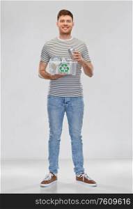 metal recycling, waste sorting and sustainability concept - smiling young man in striped t-shirt holding plastic box with tin cans over grey background. smiling young man sorting metallic waste