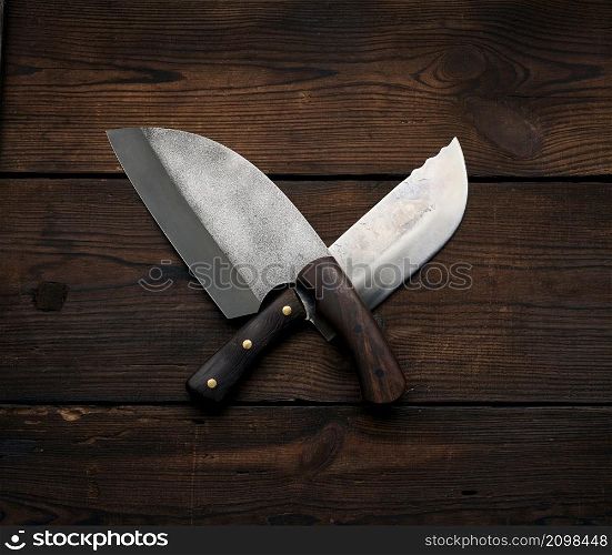 metal sharp kitchen knives in a wooden handle on a brown table made of boards, top view