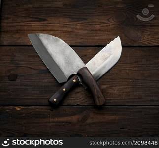 metal sharp kitchen knives in a wooden handle on a brown table made of boards, top view