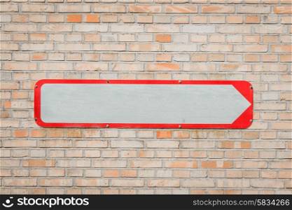 Metal sign with an arrow on a brick wall