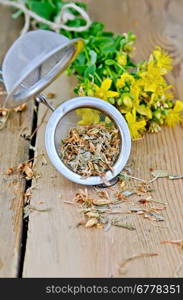 Metal strainer with dry flowers tutsan, fresh flowers tutsan against a wooden board