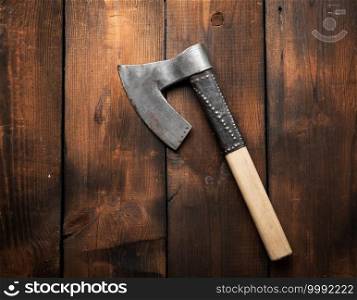 metal vintage ax with wooden handle on brown wooden background, top view