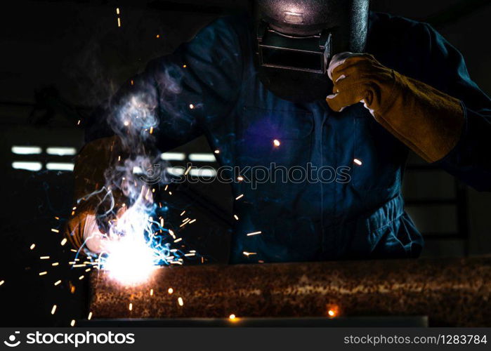 Metal welder working with arc welding machine to weld steel at factory while wearing safety equipment. Metalwork manufacturing and construction maintenance service by manual skill labor concept.. Metal welder working with arc welding machine.