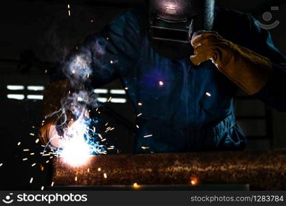 Metal welder working with arc welding machine to weld steel at factory while wearing safety equipment. Metalwork manufacturing and construction maintenance service by manual skill labor concept.. Metal welder working with arc welding machine.