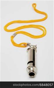 Metal whistle with a yellow cord on a grey background