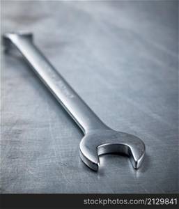 Metal wrench on the table. On a gray background. High quality photo. Metal wrench on the table.