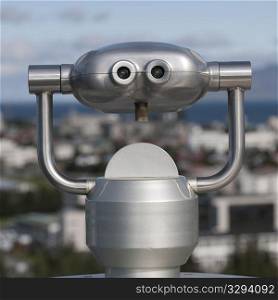 Metalic binocular viewer above city skyline