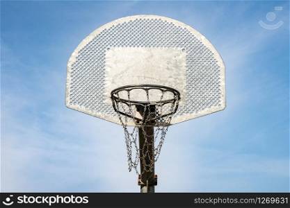 Metallic basketball board and hoop with blue sky in the background
