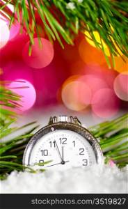 metallic clock on snow with christmas tree branch on blurred background