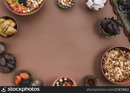 metallic earthen bowl dried fruits dates lukum nuts baklava arranged circular shapeover brown background
