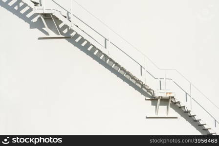 metallic staircase floating on an off-white wall background