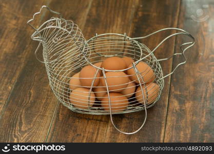 Metallic vessel shaped like a hen filled with eggs on a wooden table