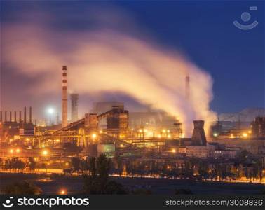 Metallurgical plant at night. Steel factory with smokestacks. Steelworks, iron works. Heavy industry in Europe. Air pollution from smokestacks, ecology problems. Industrial landscape at dusk. Plant