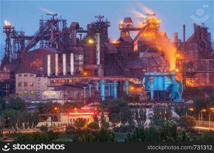 Metallurgical plant at night. Steel factory with smokestacks. Steelworks, iron works. Heavy industry in Europe. Air pollution from smokestacks, ecology problems. Industrial landscape at twilight