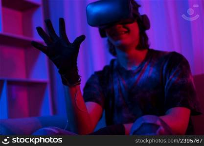 Metaverse technology concept, Man wear VR goggles and glove to making gesture while playing games.