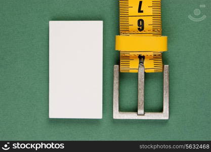 meter belt slimming and blank business card on the green background